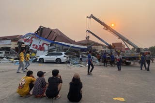 As pessoas olham para a casa danificada no mercado de Thapyaygone após um terremoto em Naypyidaw, Mianmar
